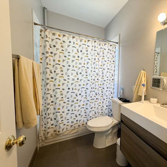 a bathroom with a toilet, sink, and shower curtain.