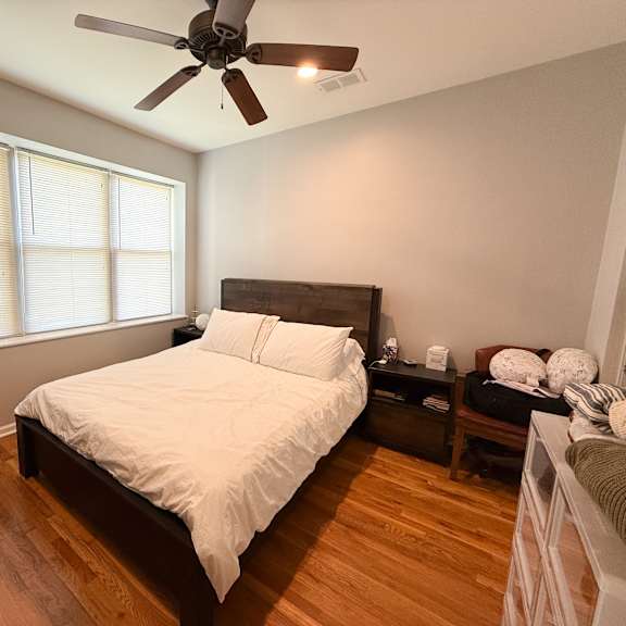 a bedroom with a bed, nightstand, and a ceiling fan.