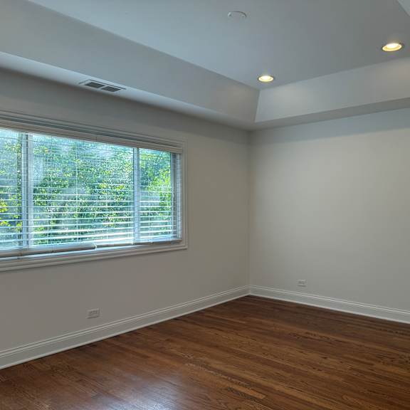 a room with wooden floors and a window with blinds.