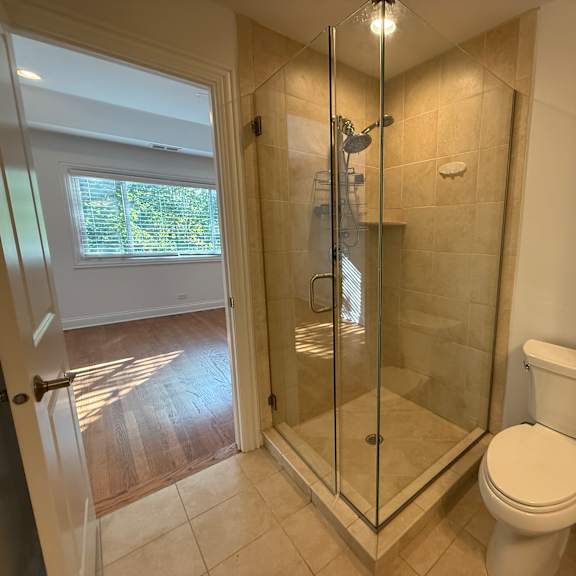 a white toilet sits in a bathroom with a walk-in shower.