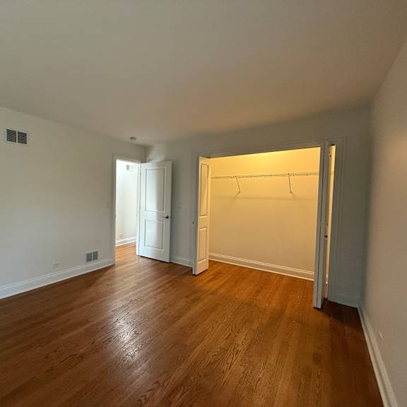 a room with a wooden floor and a white wall with a doorway leading to another room.