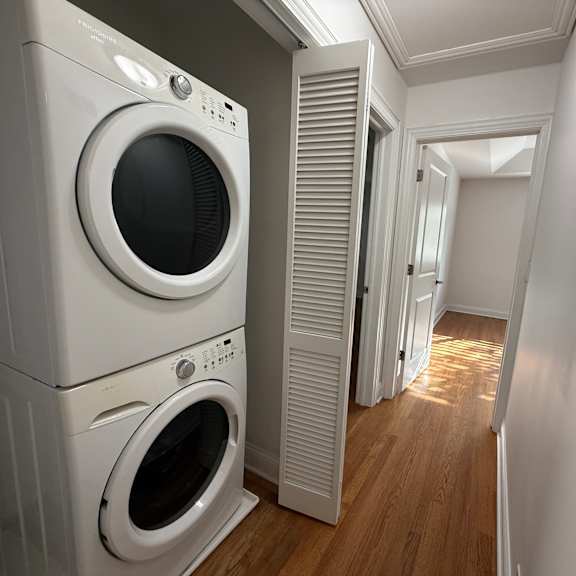 a row of white front loading washing machines in a laundry room.