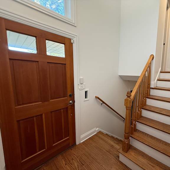a wooden staircase with a white wall and a wooden door.