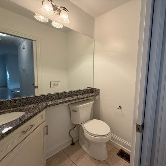 a white toilet in a bathroom with a granite counter top.