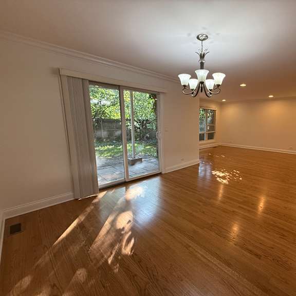 a large empty room with wooden floors and a chandelier.