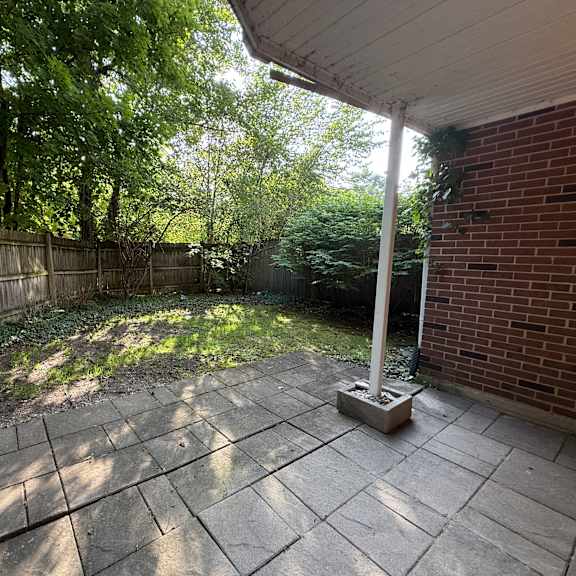 a patio with a white pillar and a brick wall.