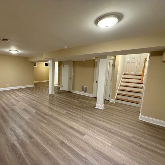 a room with wooden flooring and a staircase in the background.