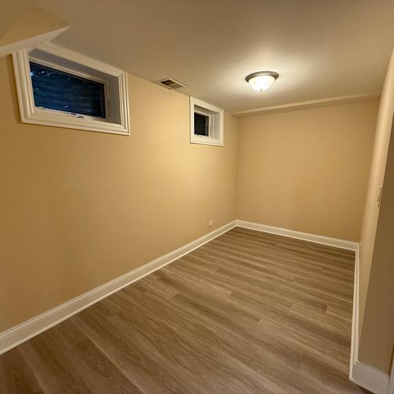 a room with wooden flooring and two windows.