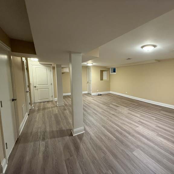 a long hallway with wood flooring and white walls.