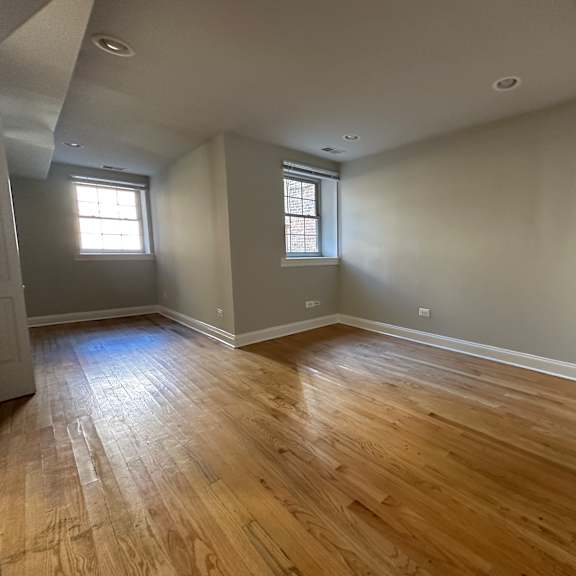 a room with wooden floors and two windows.