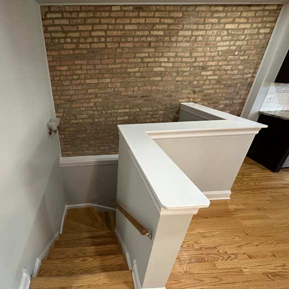 a staircase with a white railing and wooden steps leading up to a white platform.