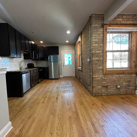 a kitchen with wooden floors and a brick wall.