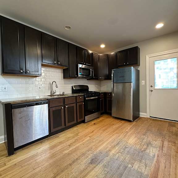 a kitchen with wooden floors and stainless steel appliances.