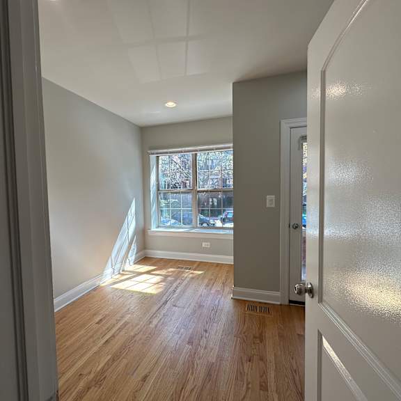 a room with wooden floors and a window with a view of a city.