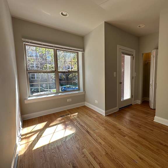 a room with wooden floors and a window letting in sunlight.