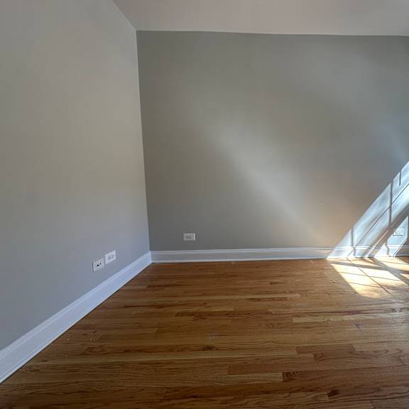 a room with wooden flooring and a window letting in sunlight.