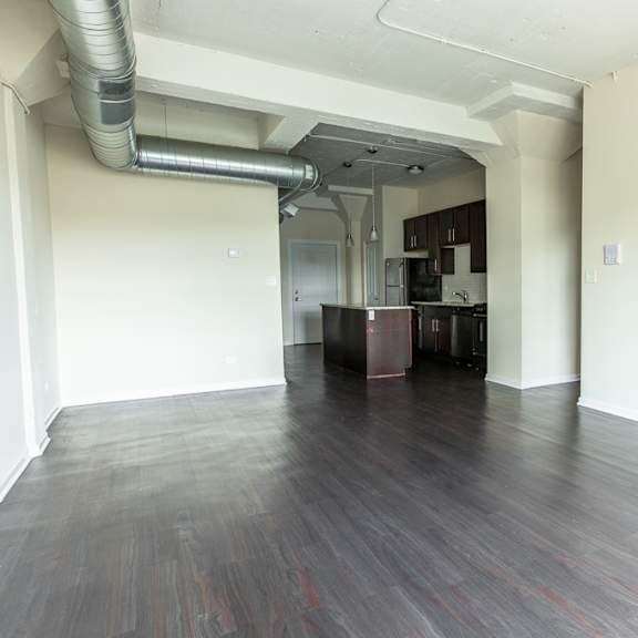 a room with a kitchen area in the background.