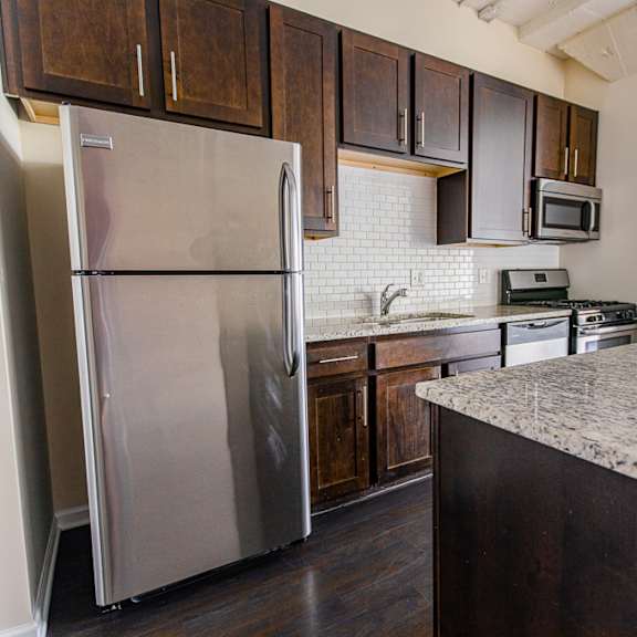 a kitchen with a stainless steel refrigerator and dark wood cabinets.