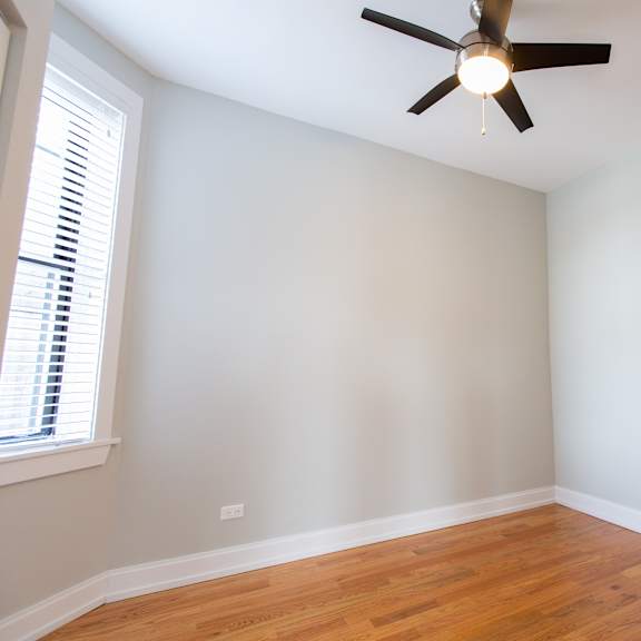 a room with a ceiling fan and wooden floors.