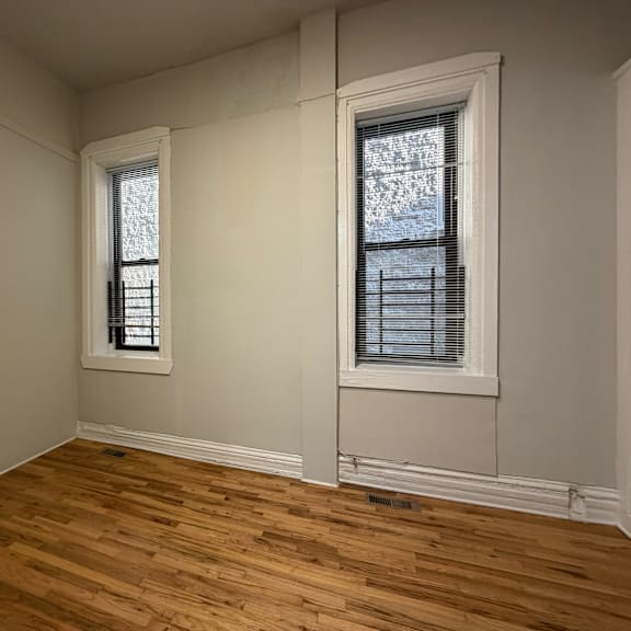 a room with two windows and wooden flooring.