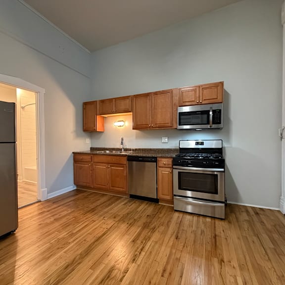 a kitchen with wooden floors and stainless steel appliances.