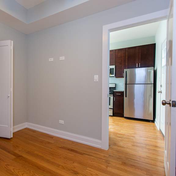 a kitchen with a refrigerator and a wooden floor.