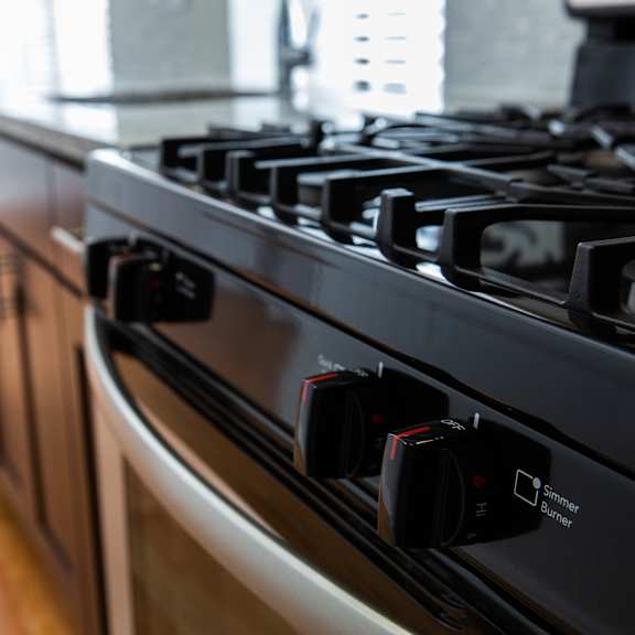 a black stove top with four knobs and a power switch.