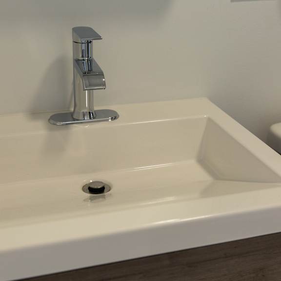 a white sink with a silver faucet and a drain in the middle.