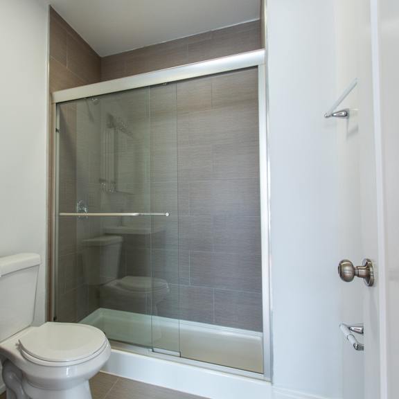 a white toilet sits in a bathroom next to a sink and a glass shower door.