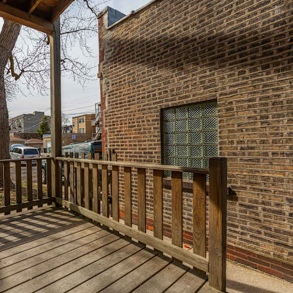 a wooden deck with a brick wall and a window.
