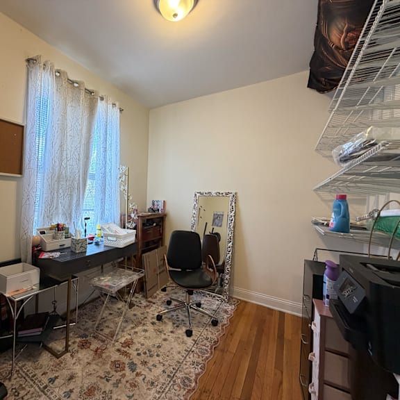 a room with a desk, chair, and a vacuum cleaner.