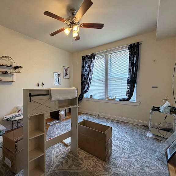 a room with a ceiling fan and a bed in it.