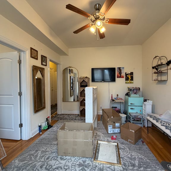 a room with a ceiling fan and boxes on the floor.