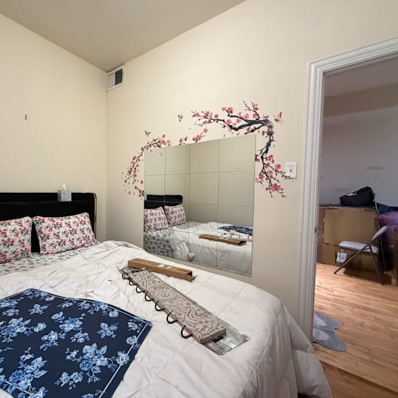 a bedroom with a large bed and a mirror with a cherry blossom design on it.