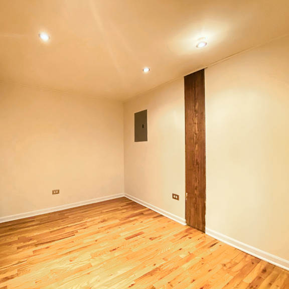 a room with wooden floors and a white wall with a brown door.