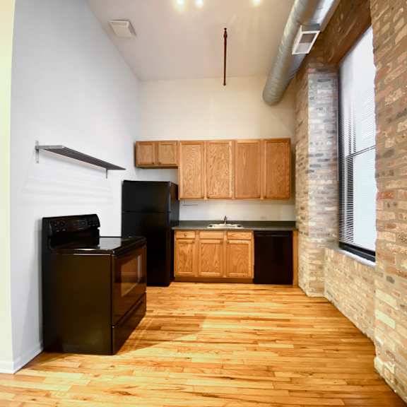 a kitchen with wooden floors and a brick column.