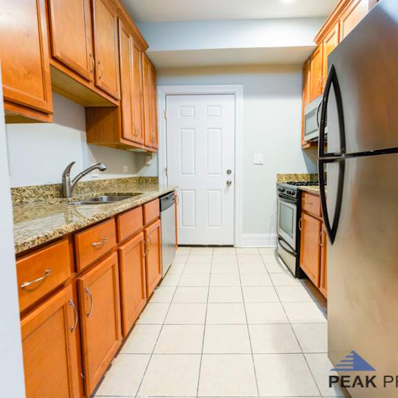 a kitchen with wooden cabinets and a black refrigerator.