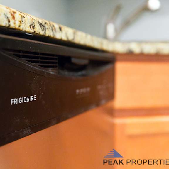 a black frigidaire refrigerator is mounted on a kitchen counter.