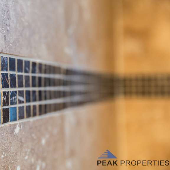 a tile wall with a logo for peak properties in the corner.