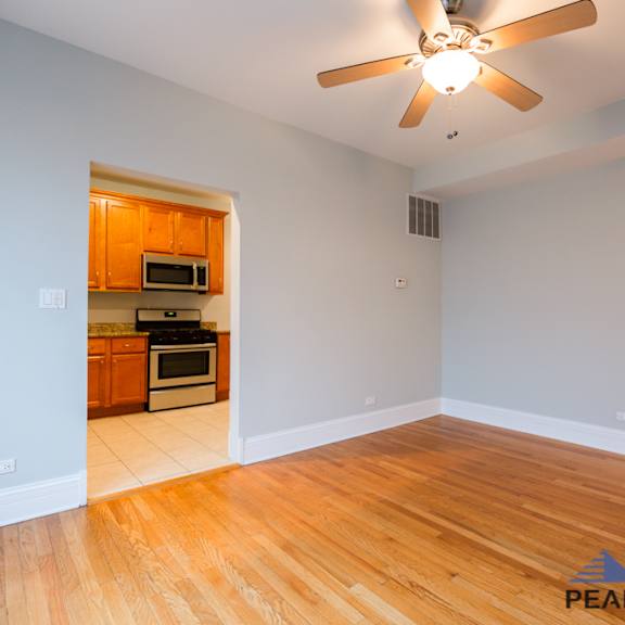 a room with a ceiling fan and wooden flooring.