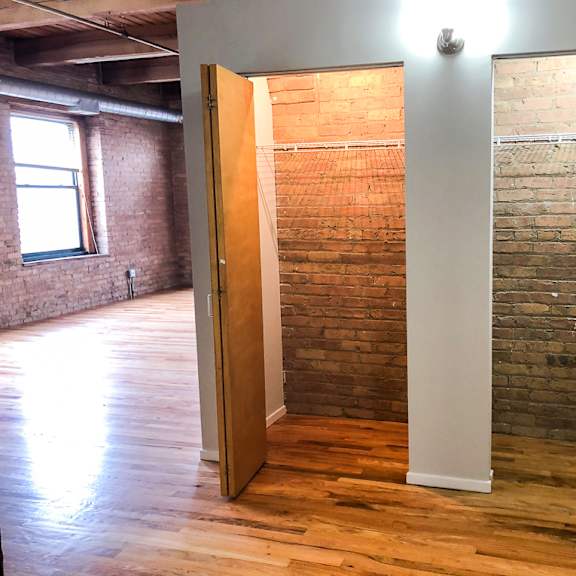 a room with a wooden floor and a brick wall.