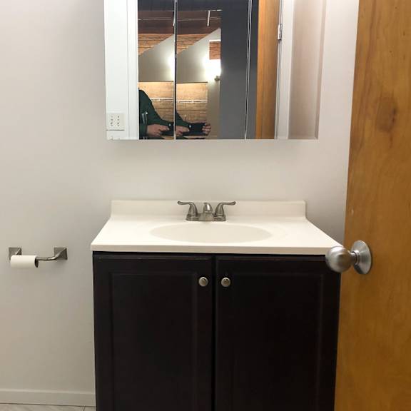 a bathroom with a white sink and a brown cabinet.