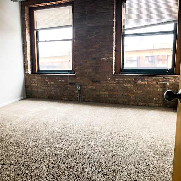 a room with a carpeted floor and two windows.