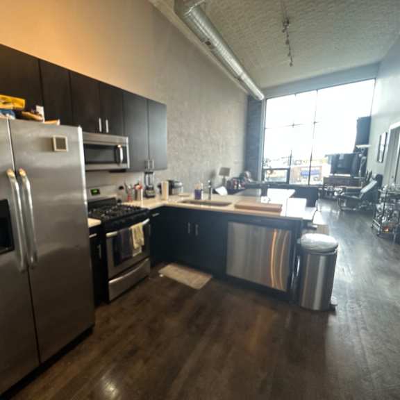 a modern kitchen with a stainless steel refrigerator and black cabinets.