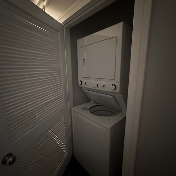 a white washing machine in a small, dark laundry room.