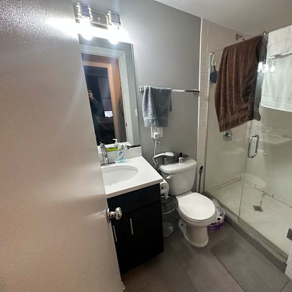 a bathroom with a toilet, sink, and shower.