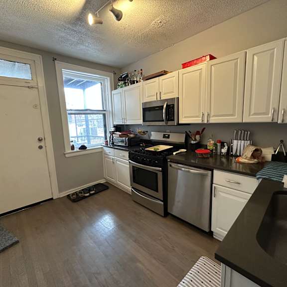 a kitchen with white cabinets and a black countertop.