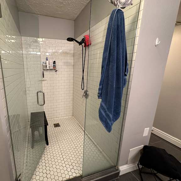a bathroom with a glass shower stall and a blue towel hanging on the door.
