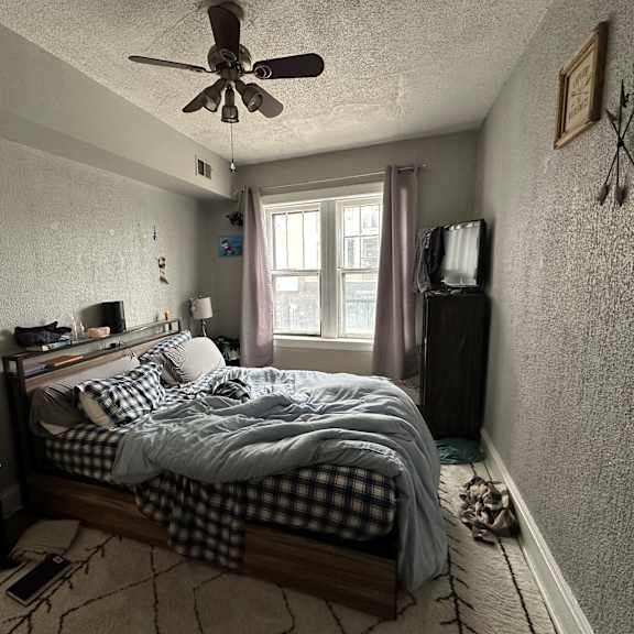 a bedroom with a bed, nightstand, and window.
