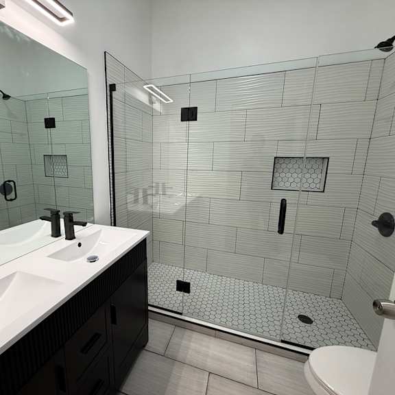 a bathroom with a walk in shower and double sinks.